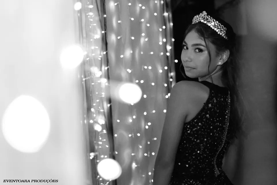 Retrato em preto e branco de uma debutante com vestido e tiara; crédito fotográfico original preservado na imagem.