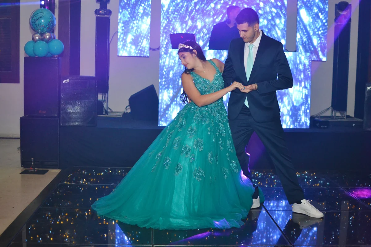 Giovana e seu acompanhante dançam, com o vestido verde em movimento.