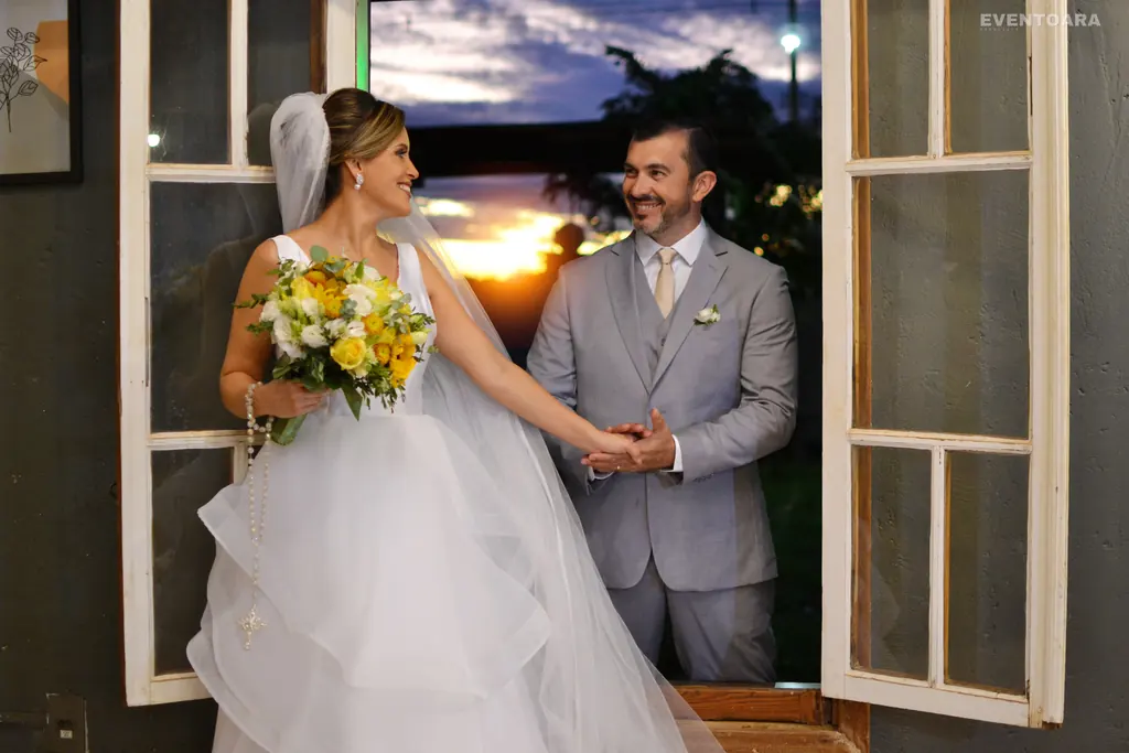 Flavio e Flavia de mãos dadas junto a uma janela ao pôr do sol, no antigo Villa Porto, em Araraquara.